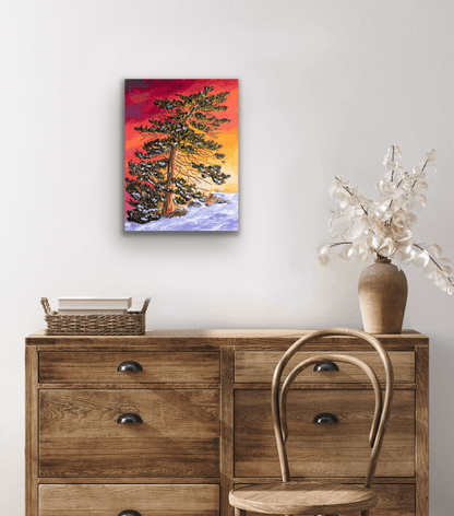 "Pining for Summer" original painting depicts a large mature tree with partial melted snow on its branches with a warm red, orange and yellow sky.